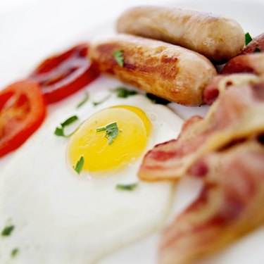 close up image of a cooked egg, sausage links, and bacon strips