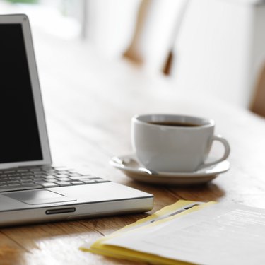 close up of a laptop on a kitchen table with a cup of coffee