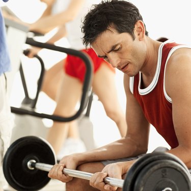 side view of a man working out with a barbell at the gym