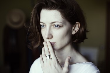 A woman covers her mouth with her hand, hiding a blister