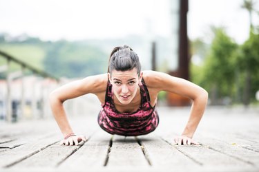 Young Woman Exercising Push-Ups on Wooden Floor.
