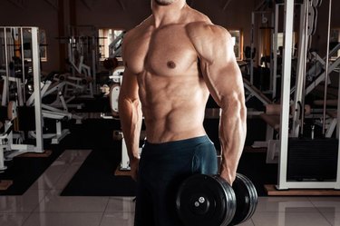 Man at the gym. Man makes exercises with dumbbells