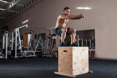 Man box jumping at a gym style gym.