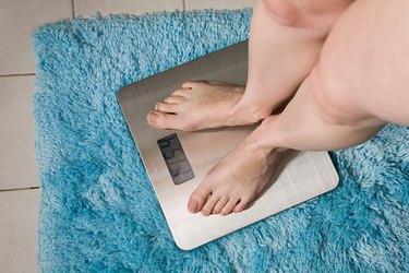 Young woman weighing herself on bathroom scales