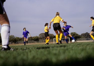 Young women playing football on grass pitch, surface view