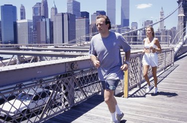 USA, New York City, man and woman jogging on Brooklyn Bridge