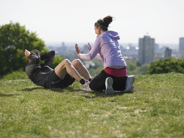 Woman helping man doing sit-ups