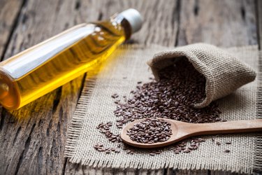 Flax seeds in the sack and oli on wooden background