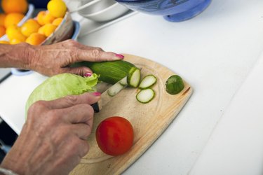 Cropped image of senior woman cutting vegetables on chopping board in kitchen
