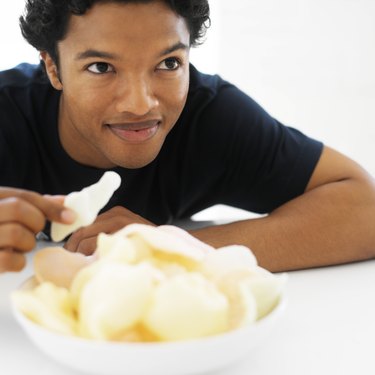 Close-up of a young man taking a prawn cracker from a bowl