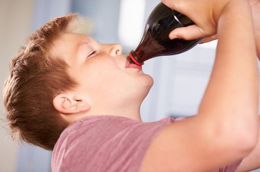 Close Up Of Boy Drinking Soda From Bottle