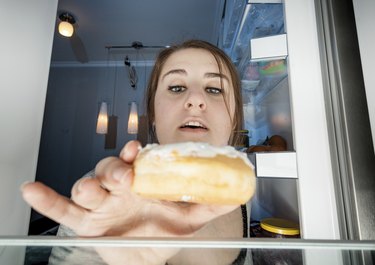 一个女人从冰箱里拿甜甜圈