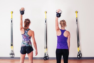 Women doing shoulder press with kettlebells