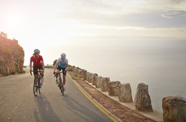 Female bike riders climbing mountain at sunset