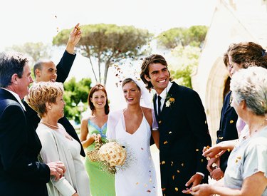 People Throwing Confetti Over a Newlywed Couple Leaving Church