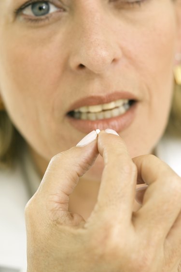 Woman taking a pill, focus on hand