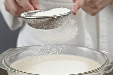 The woman cook is occupied with dough preparation