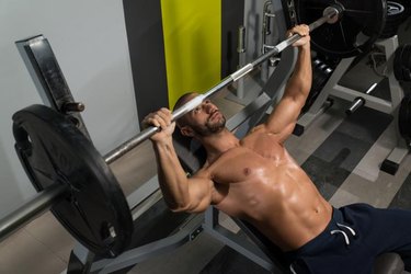 Young Man In Gym Exercising Chest On The Bench Press