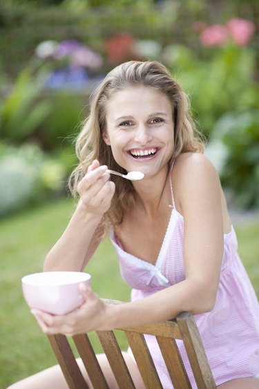 Portrait of young woman eating outdoors, smiling