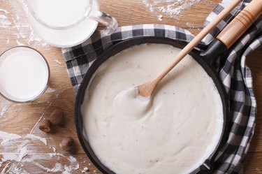 bechamel sauce in pan and milk on table top view