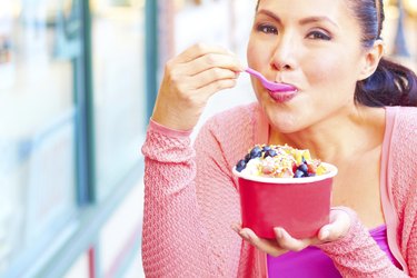 Happy Young Pretty Mixed Race Female Eating Frozen Yogurt