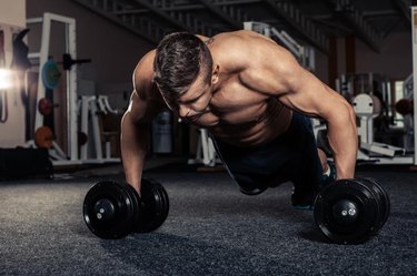 Handsome muscular man doing pushup exercise with dumbbell