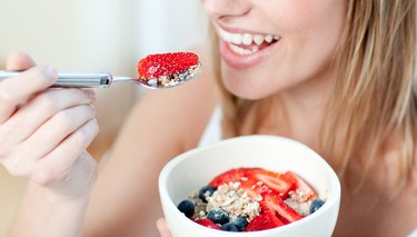 Close-up of a woman eating muesli with fruits