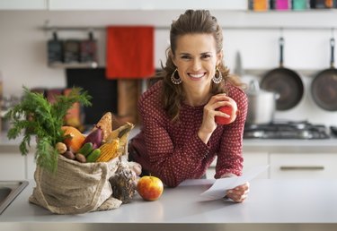 Portrait of happy housewife holding grocery shopping checks