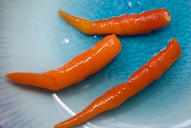 Close-up view of three red chilis on a blue plate.