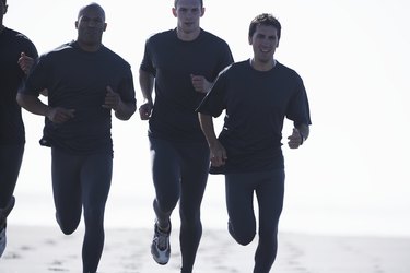 Four men jogging on beach