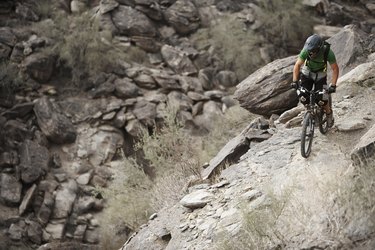 Rider mountain biking along cliff