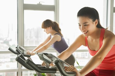 Young women on stationary bikes exercising in the gym