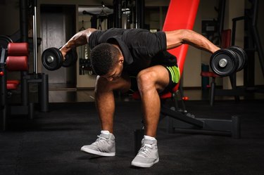 handsome young african descent mixed race man doing Seated Bent Over Dumbbell Reverse Fly workout in gym