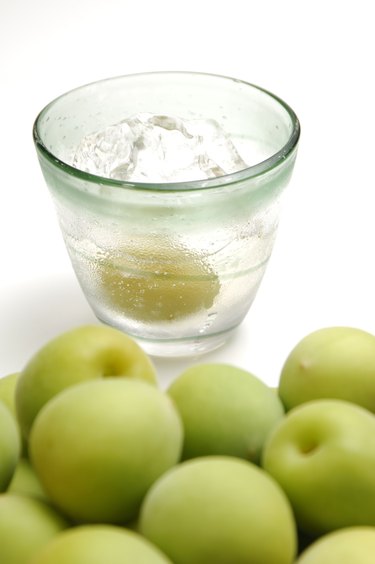 Unripe plums and glass of plum liquor.
