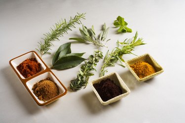 Barbecue scene, fresh herbs and spices laid out on white background.