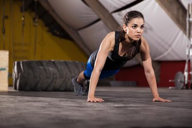 Gorgeous and strong brunette doing a set of push ups in a gym gym