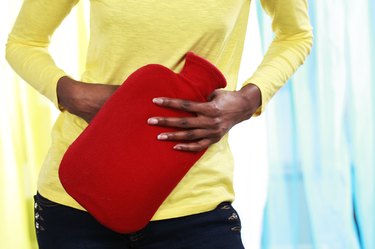 African woman with hot bottle and stomach pain