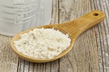 whey protein powder in a wooden spoon on a wooden table