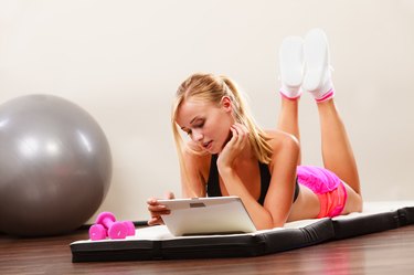 Fit woman lying on floor with tablet pc