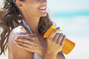 closeup on smiling young woman applying sun block creme