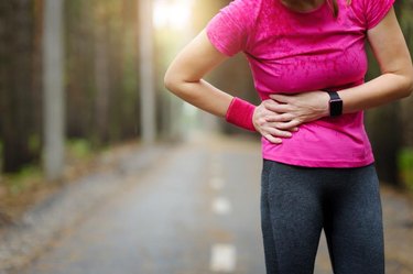 Side stitch - woman runner side cramps. Marathon.