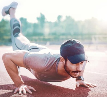 Picture of a young athletic man doing push ups outdoors, fitness and exercising in the park. Sport concept