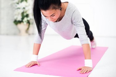 Young latin woman warming up and doing push ups at home fitness healthy lifestyle and diet concept