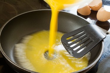 beaten egg flowing into the pan for scrambled eggs
