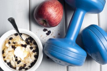 Dumbbells and red apple next to bowl with yogurt