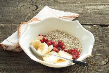 Oatmeal, banana and frozen strawberries in white bowl