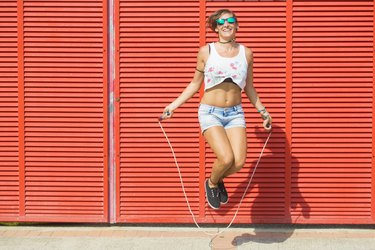 Woman jumping rope on red background