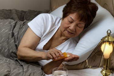 Senior woman taking her medicine at nighttime due to sickness