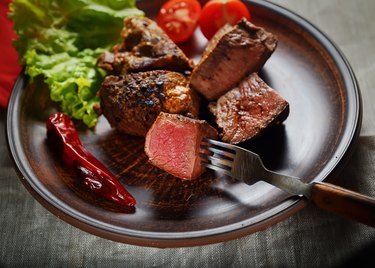 piece of steak on a fork, salad and vegetables