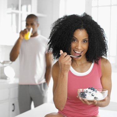 Portrait of a young woman eating ice cream and fruit from a bowl